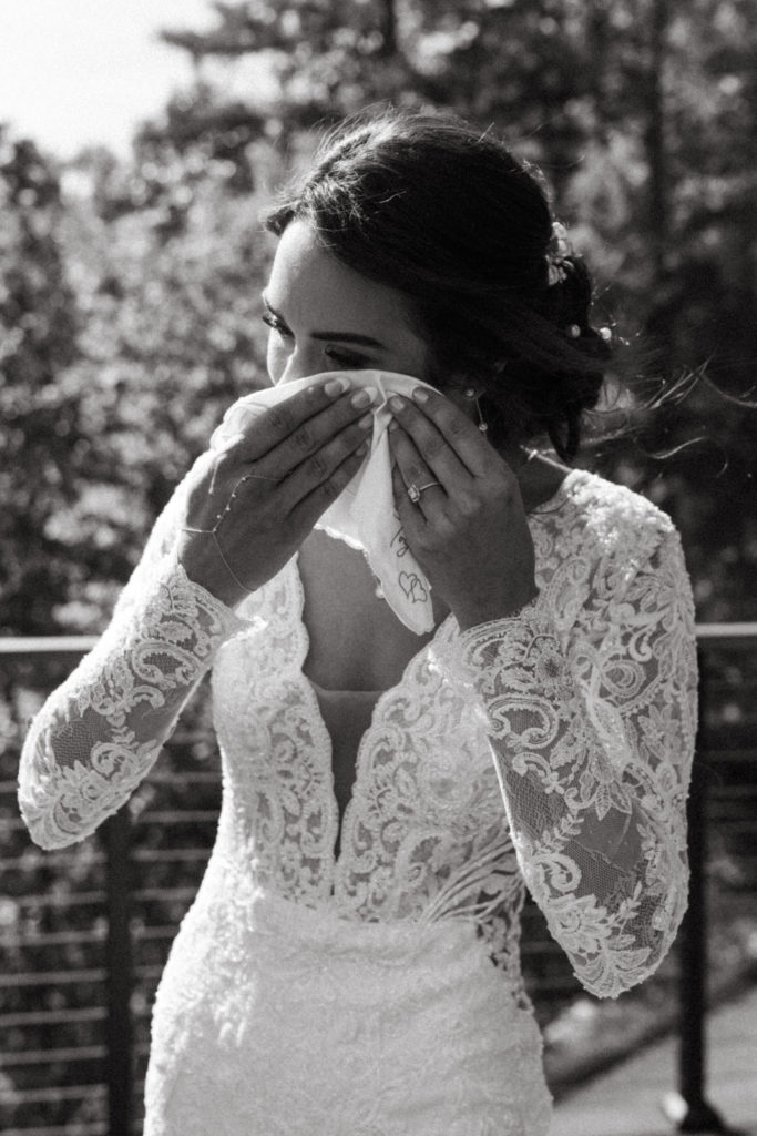 bride wiping tear away after emotional first look